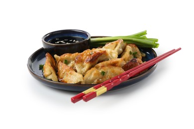 Photo of Tasty fried gyoza (dumplings), onion, chopsticks and soy sauce isolated on white