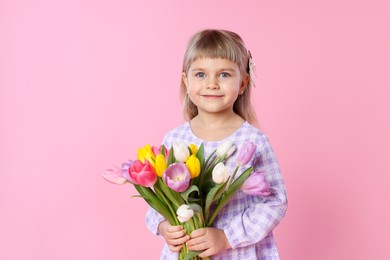 Photo of Cute little girl with bouquet of tulips on pink background. Space for text