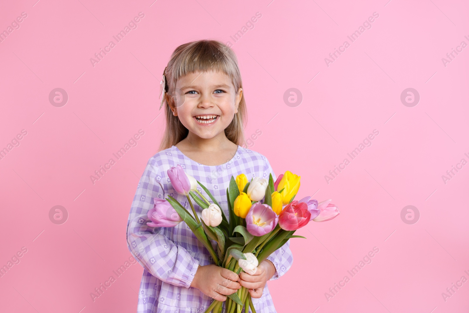 Photo of Happy little girl with bouquet of tulips on pink background