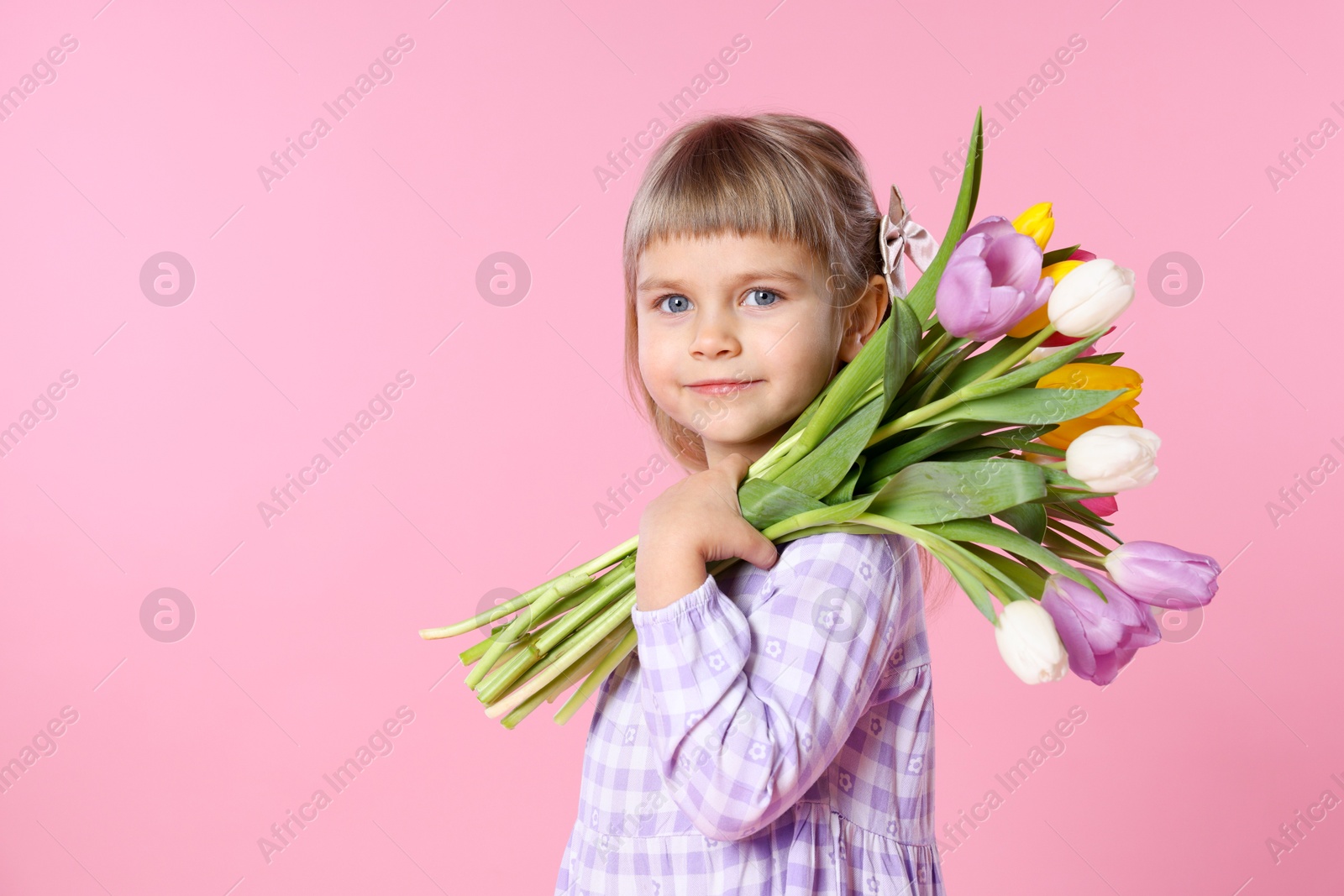 Photo of Cute little girl with bouquet of tulips on pink background. Space for text