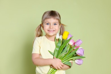 Photo of Smiling little girl with bouquet of tulips on green background