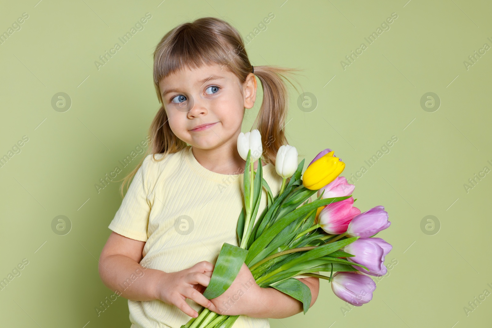 Photo of Cute little girl with bouquet of tulips on green background