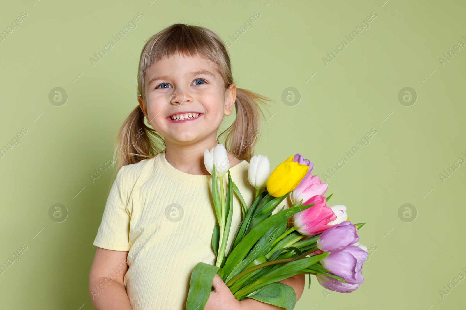 Photo of Smiling little girl with bouquet of tulips on green background