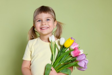 Photo of Smiling little girl with bouquet of tulips on green background