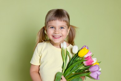 Photo of Smiling little girl with bouquet of tulips on green background