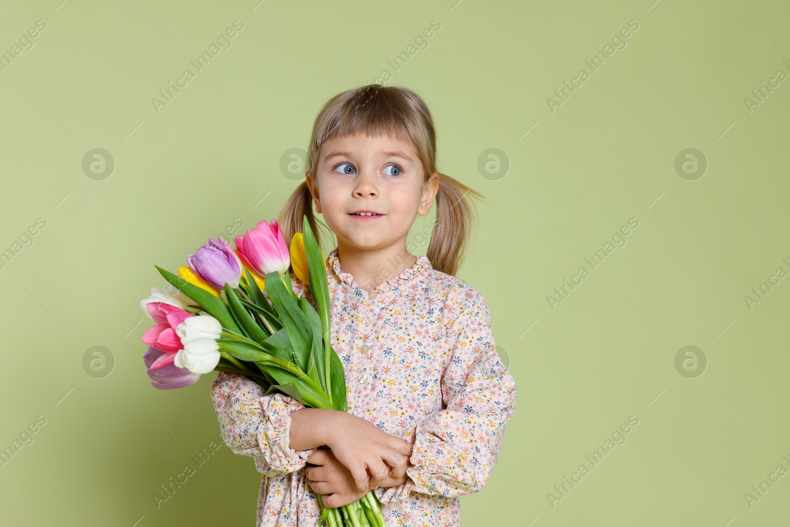 Photo of Smiling little girl with bouquet of tulips on green background