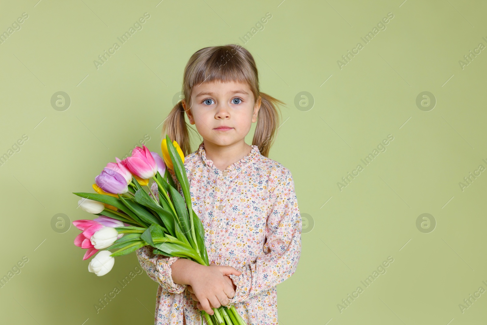 Photo of Cute little girl with bouquet of tulips on green background