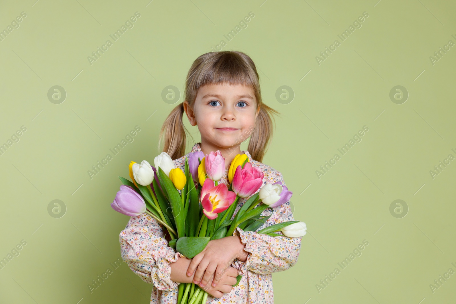 Photo of Cute little girl with bouquet of tulips on green background