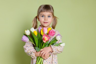 Photo of Cute little girl with bouquet of tulips on green background