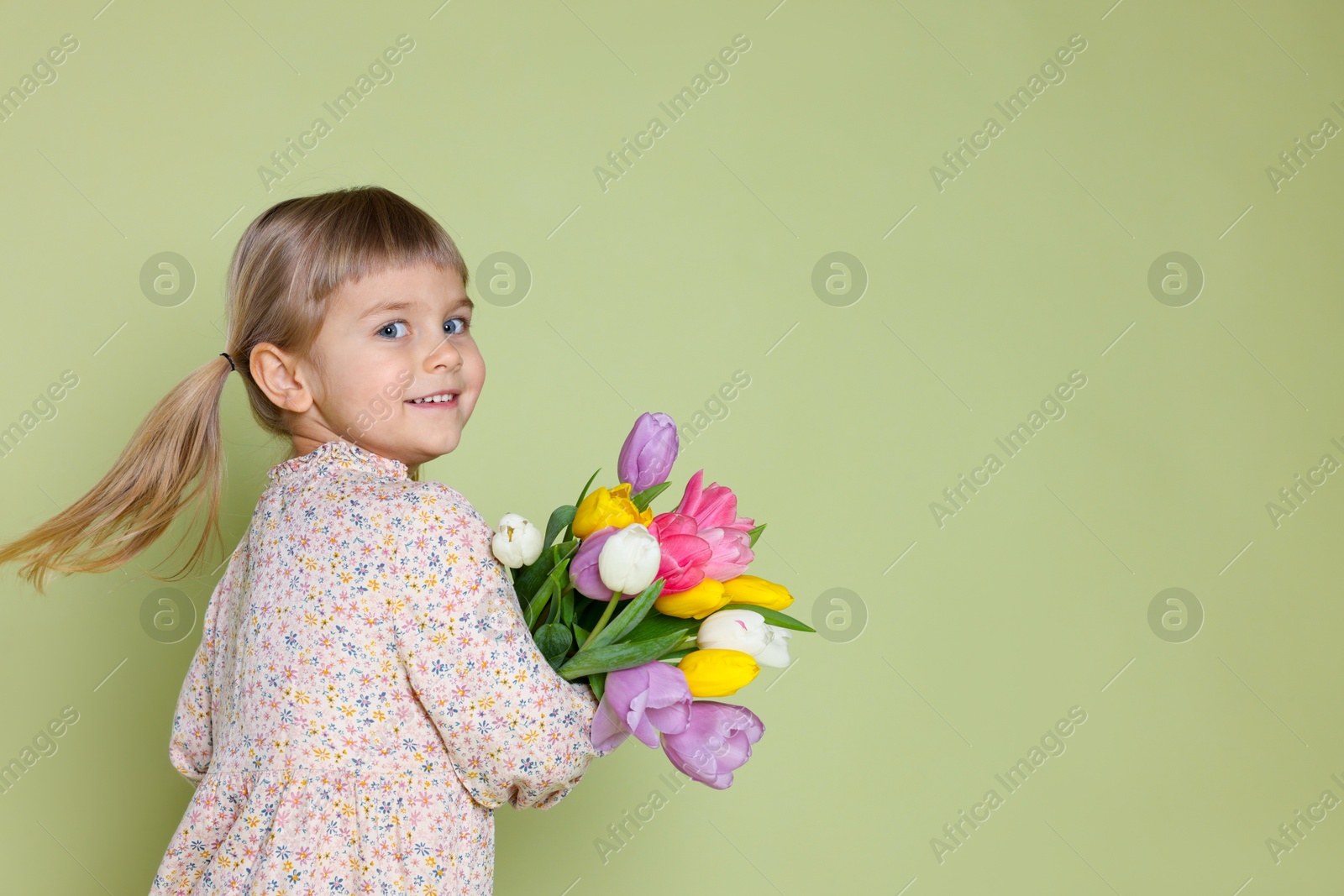 Photo of Smiling little girl with bouquet of tulips on green background. Space for text