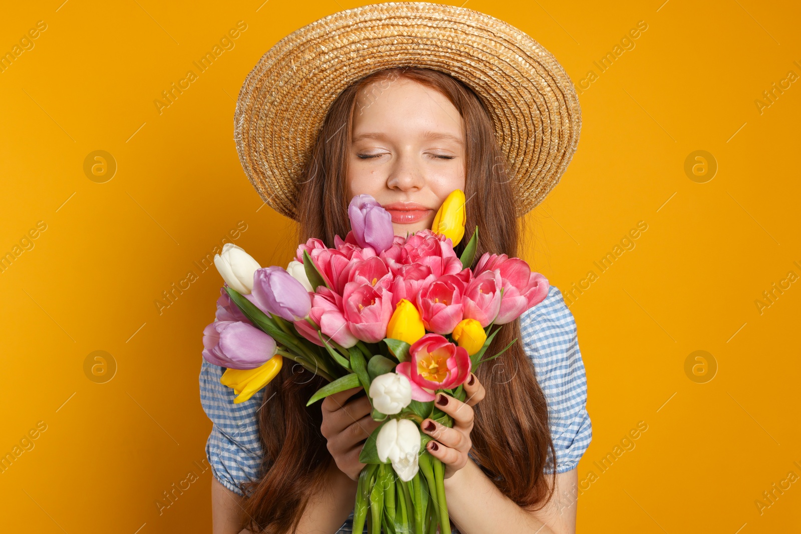 Photo of Beautiful teenage girl with bouquet of tulips on orange background