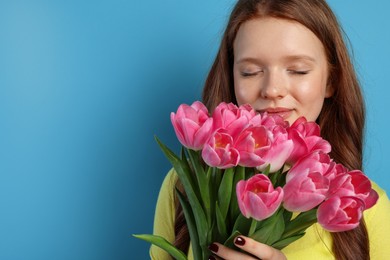 Beautiful teenage girl with bouquet of tulips on light blue background, space for text