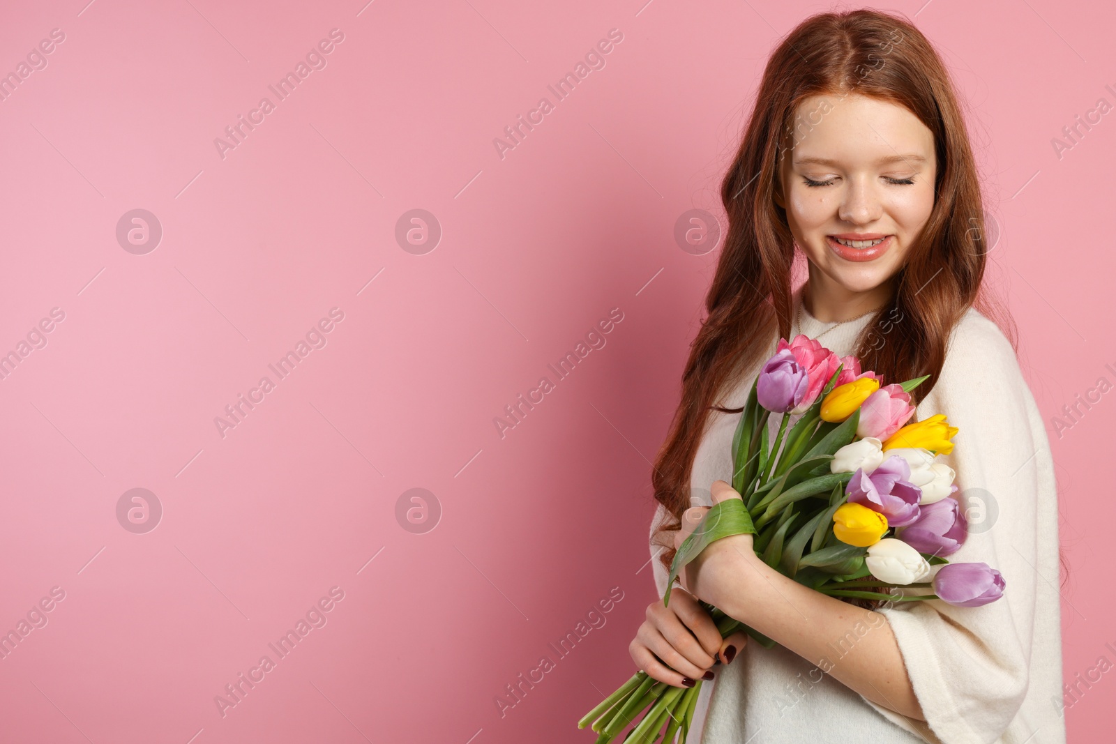 Photo of Beautiful teenage girl with bouquet of tulips on pink background, space for text