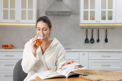 Photo of Beautiful woman drinking juice after spa procedure in kitchen, space for text