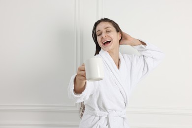 Photo of Spa day. Beautiful woman with face mask and cup of drink indoors, space for text