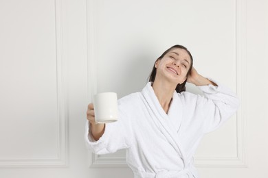 Photo of Spa day. Beautiful woman with face mask and cup of drink indoors, space for text