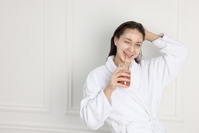 Photo of Spa day. Beautiful woman with face mask drinking juice indoors, space for text