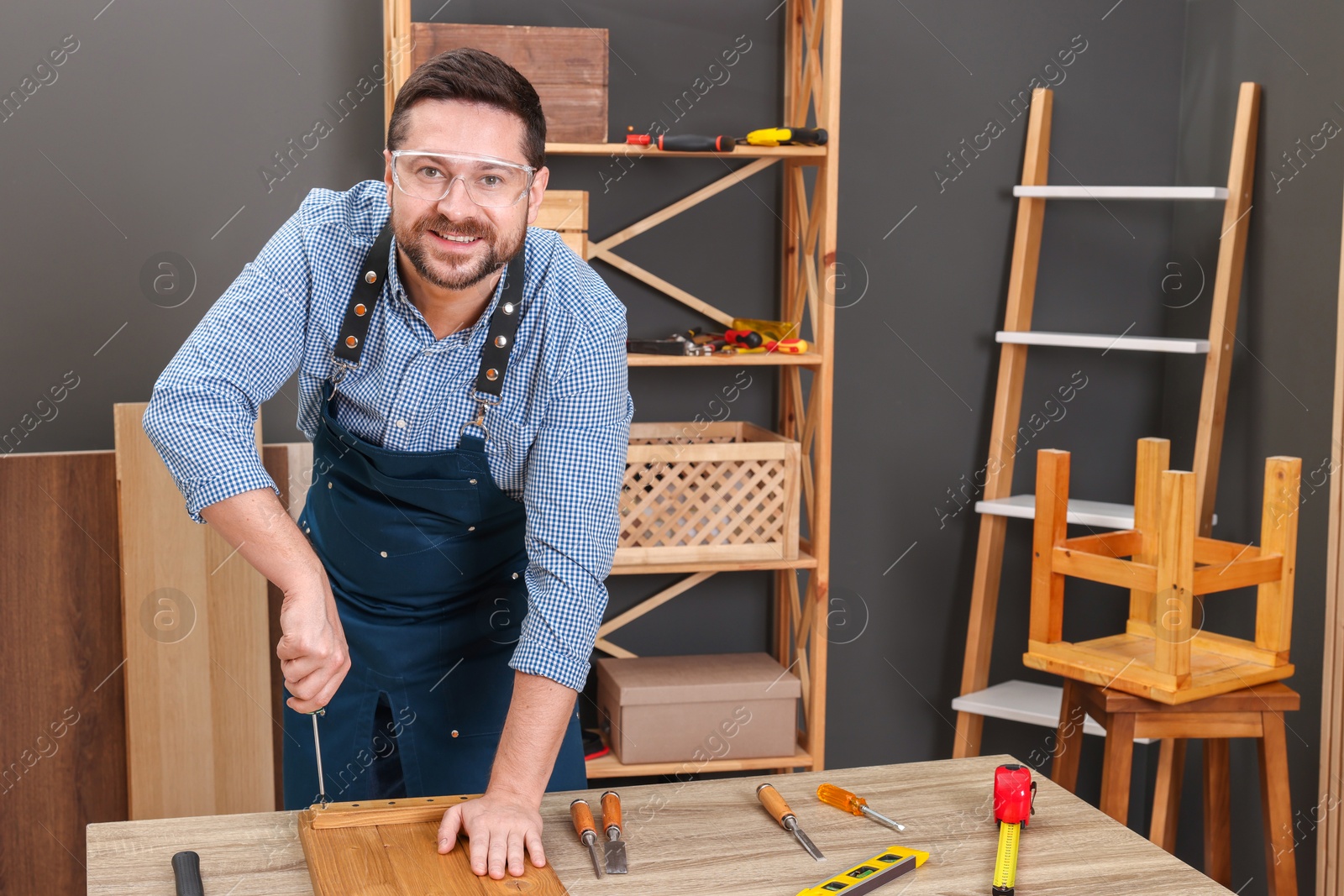 Photo of Relaxing hobby. Man working with wooden plank and screwdriver at table in workshop