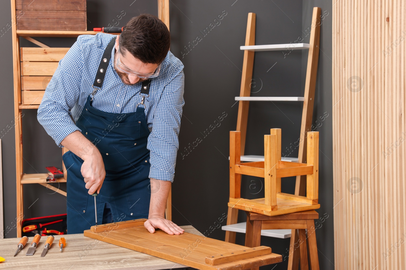 Photo of Relaxing hobby. Man working with wooden plank and screwdriver at table in workshop