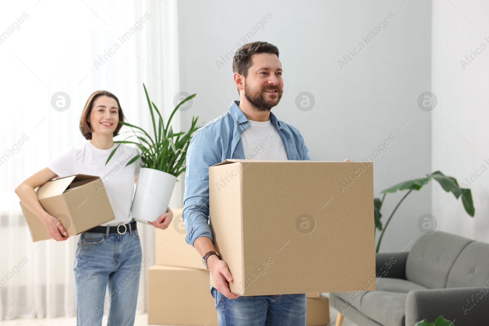 Photo of Moving day. Happy couple with cardboard boxes in their new home, selective focus