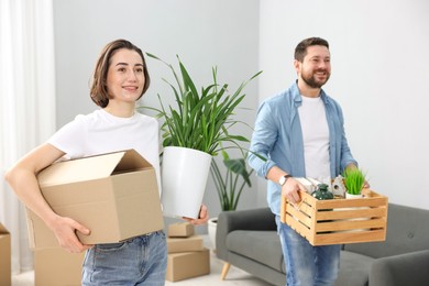 Photo of Moving day. Happy couple with boxes in their new home, selective focus