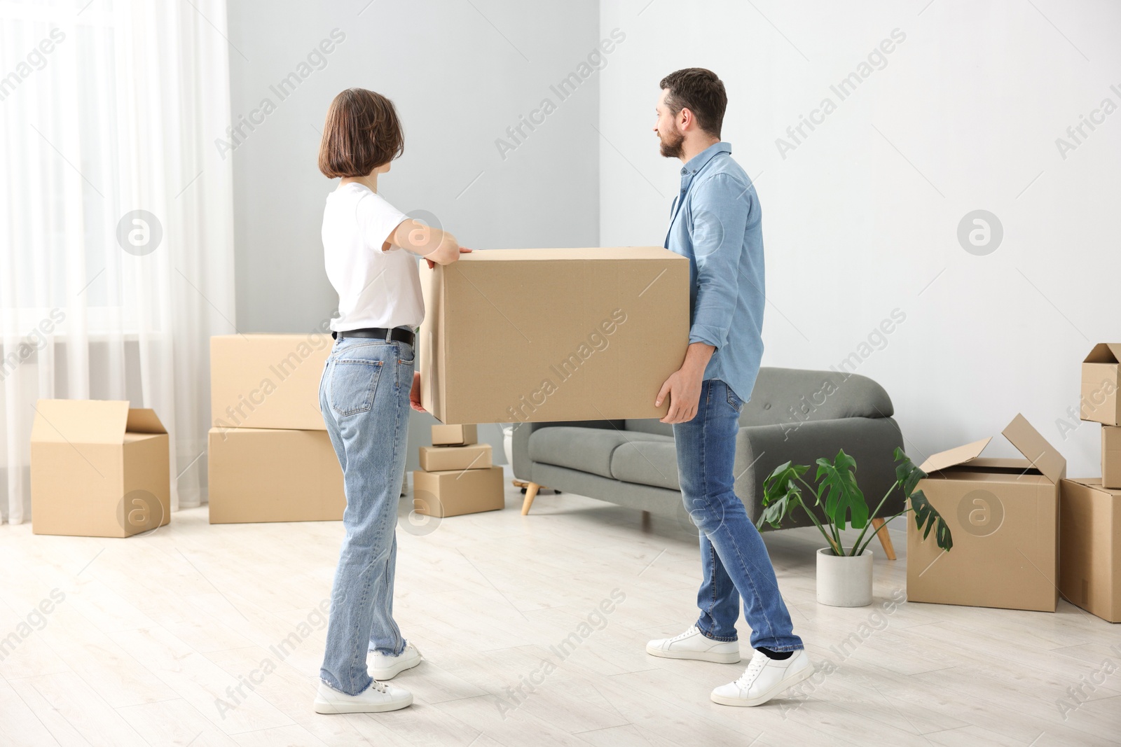 Photo of Moving day. Happy couple carrying box in their new home