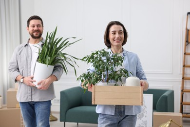 Photo of Moving day. Happy couple with their belongings in new home, selective focus