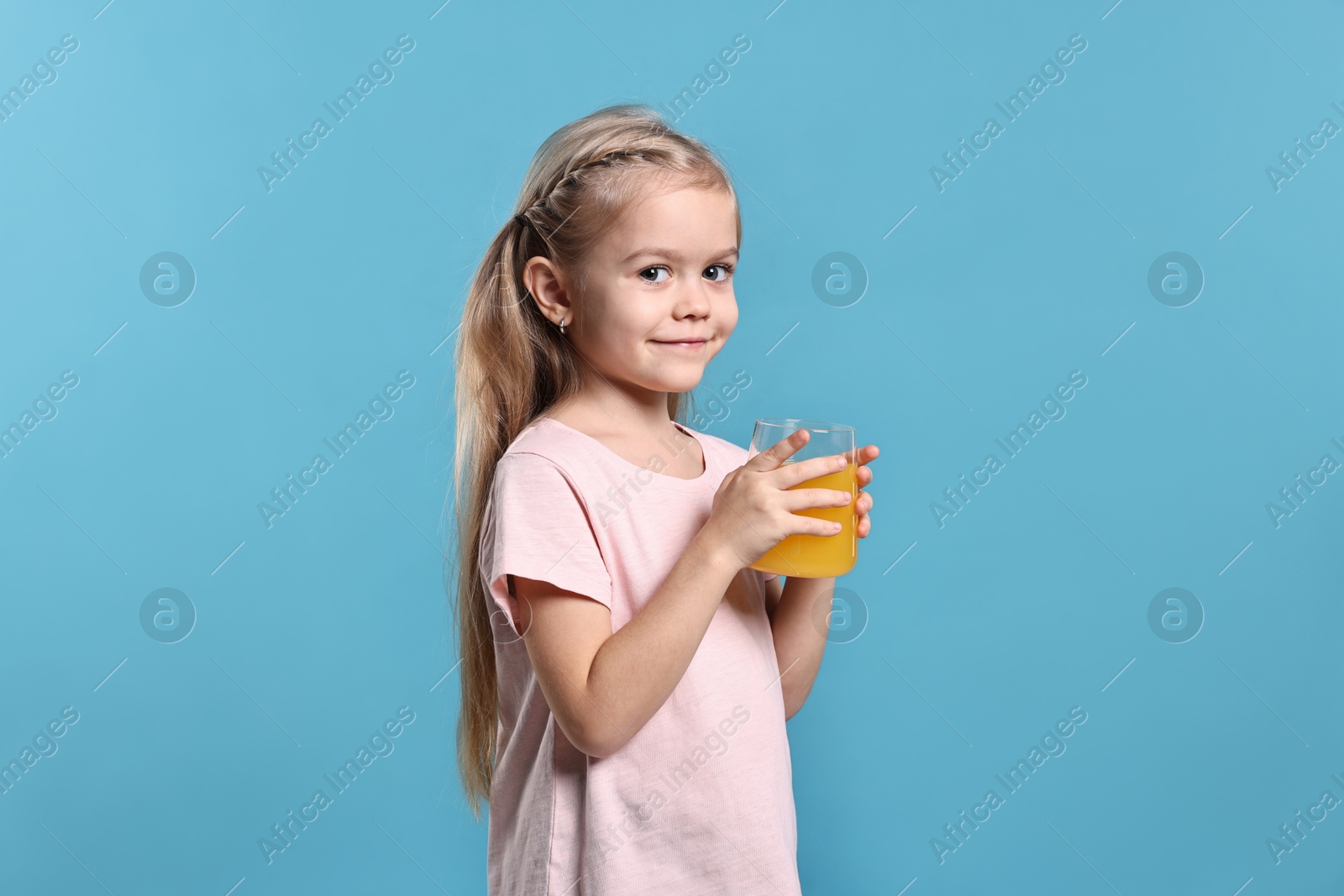 Photo of Girl with glass of orange juice on light blue background. Refreshing drink