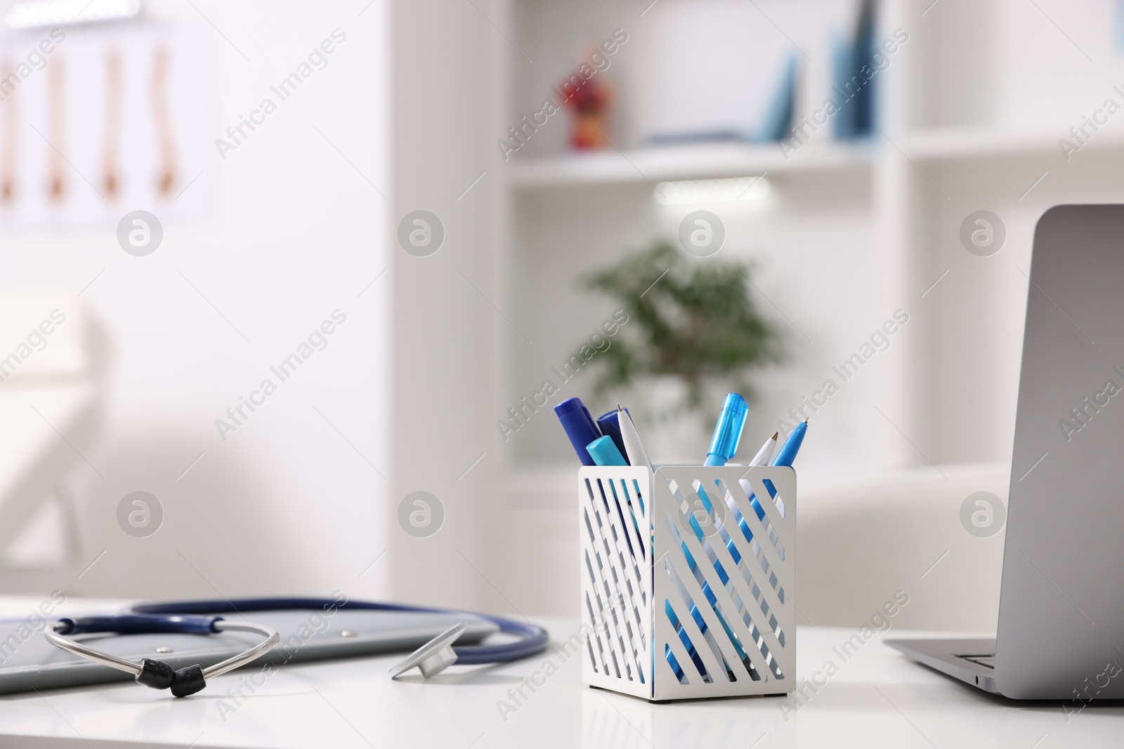 Photo of Laptop, stethoscope and folders on desk in medical office, closeup