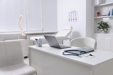 Photo of Laptop, stethoscope and folders on desk in medical office