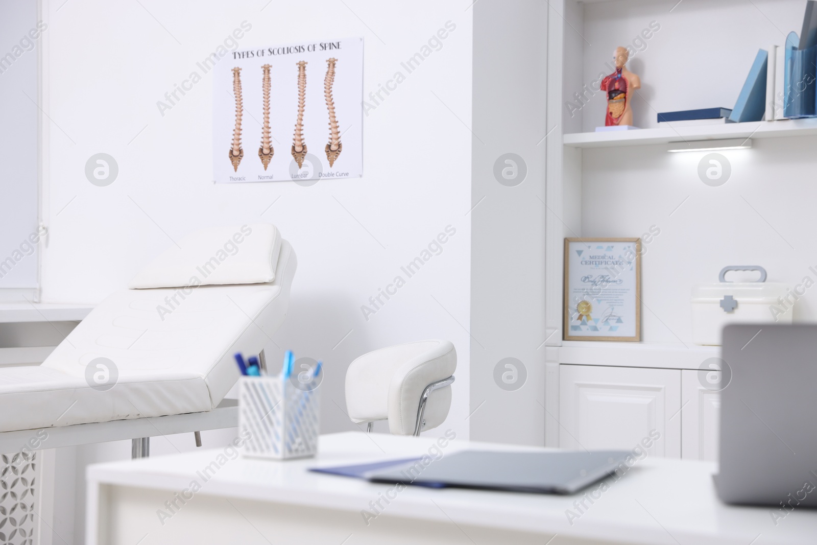 Photo of Laptop and folders on desk in medical office, closeup