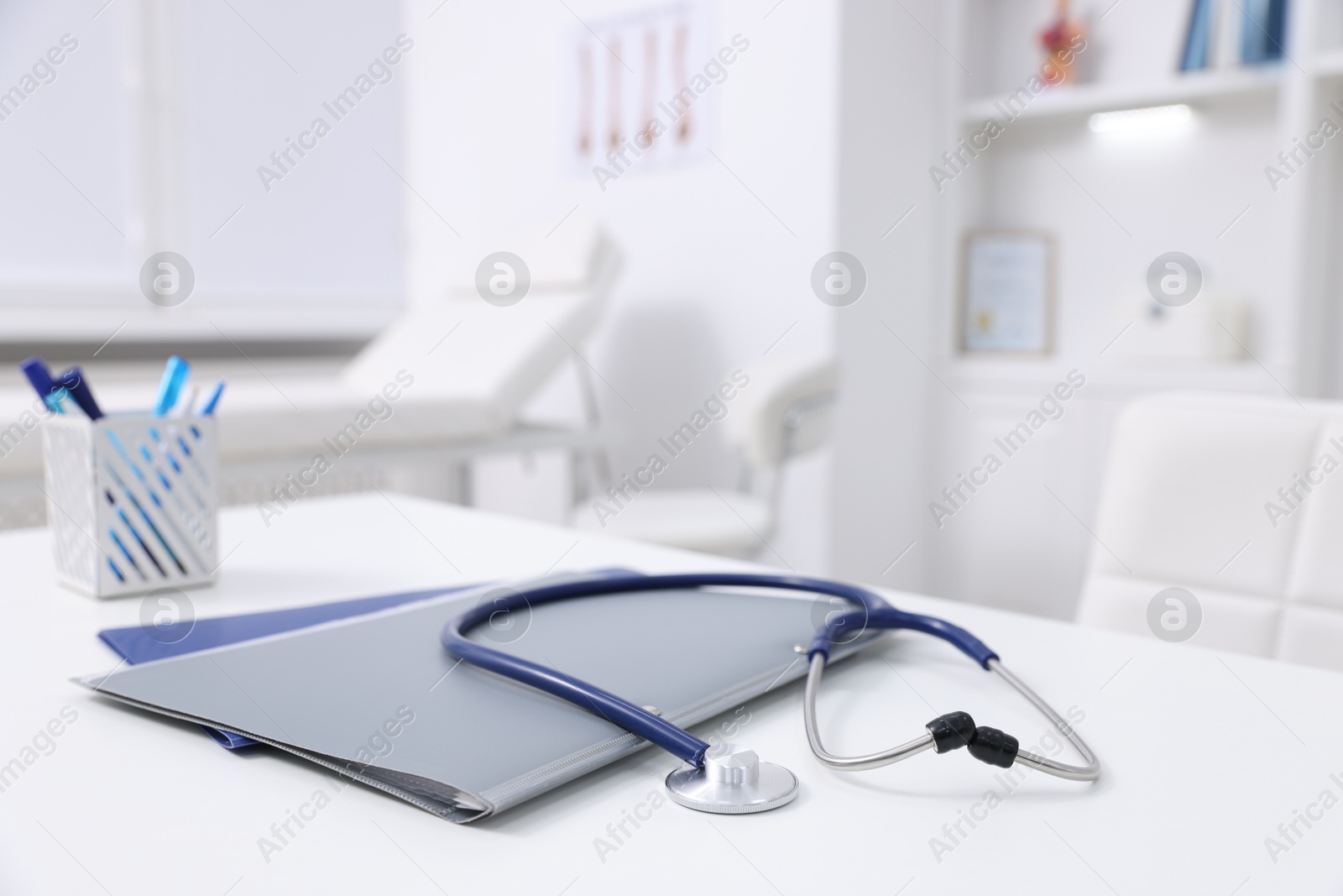 Photo of Stethoscope and folders on desk in medical office, closeup