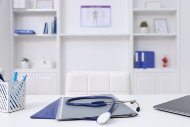 Photo of Stethoscope and folders on desk in medical office, closeup