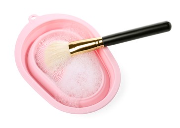 Photo of Makeup brush with soap and cleansing pad isolated on white, above view