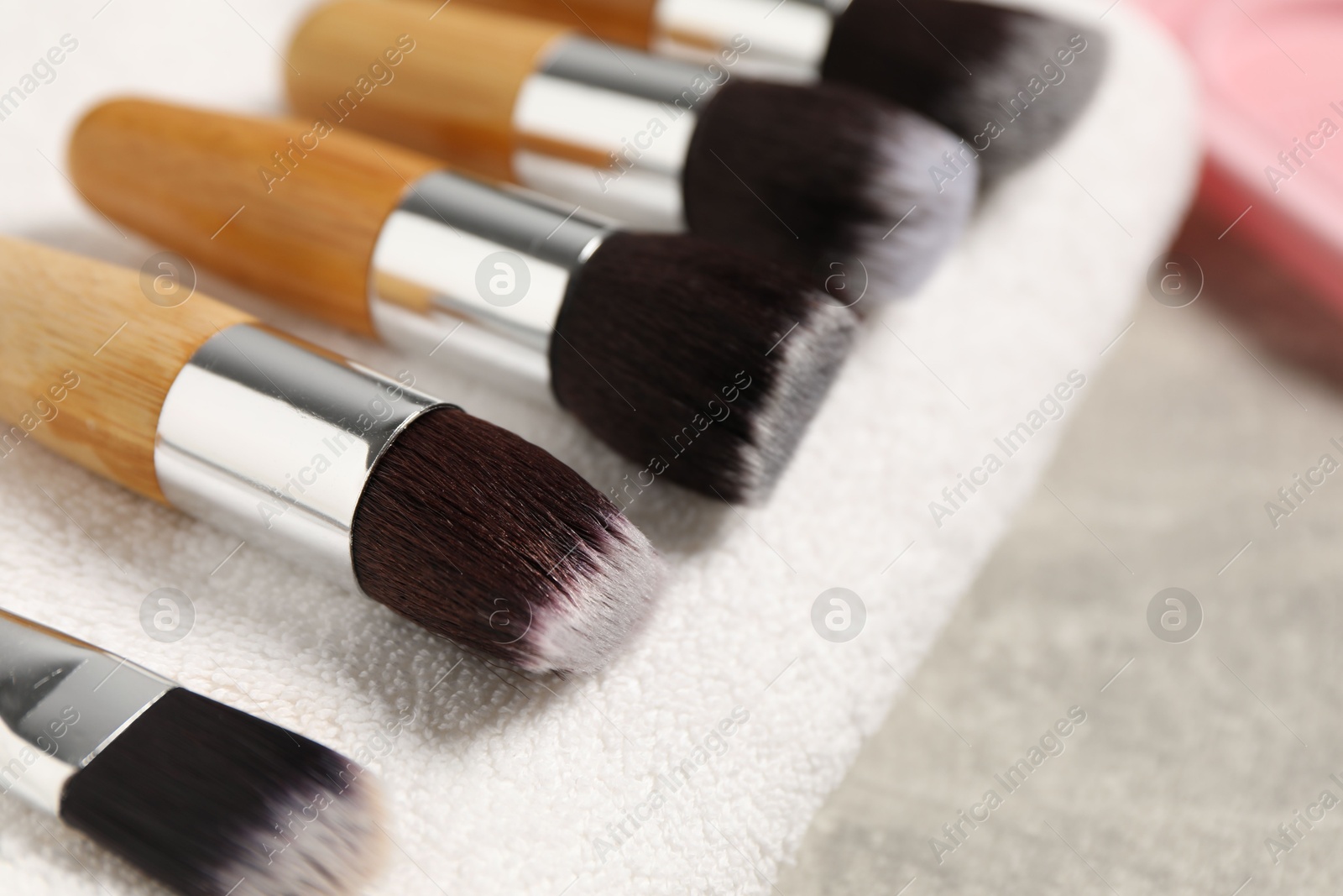 Photo of Clean makeup brushes with towel on grey table, closeup. Space for text