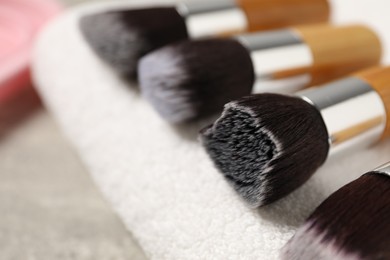 Photo of Clean makeup brushes with towel on grey table, closeup. Space for text