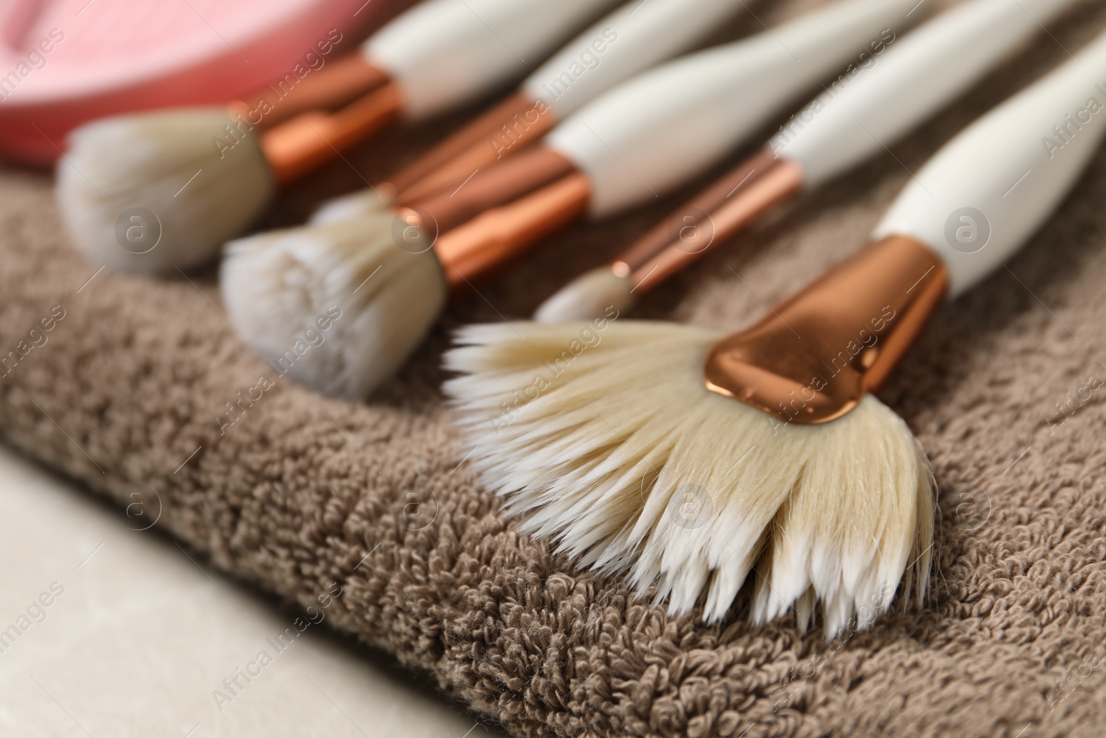 Photo of Clean makeup brushes with towel on grey table, closeup