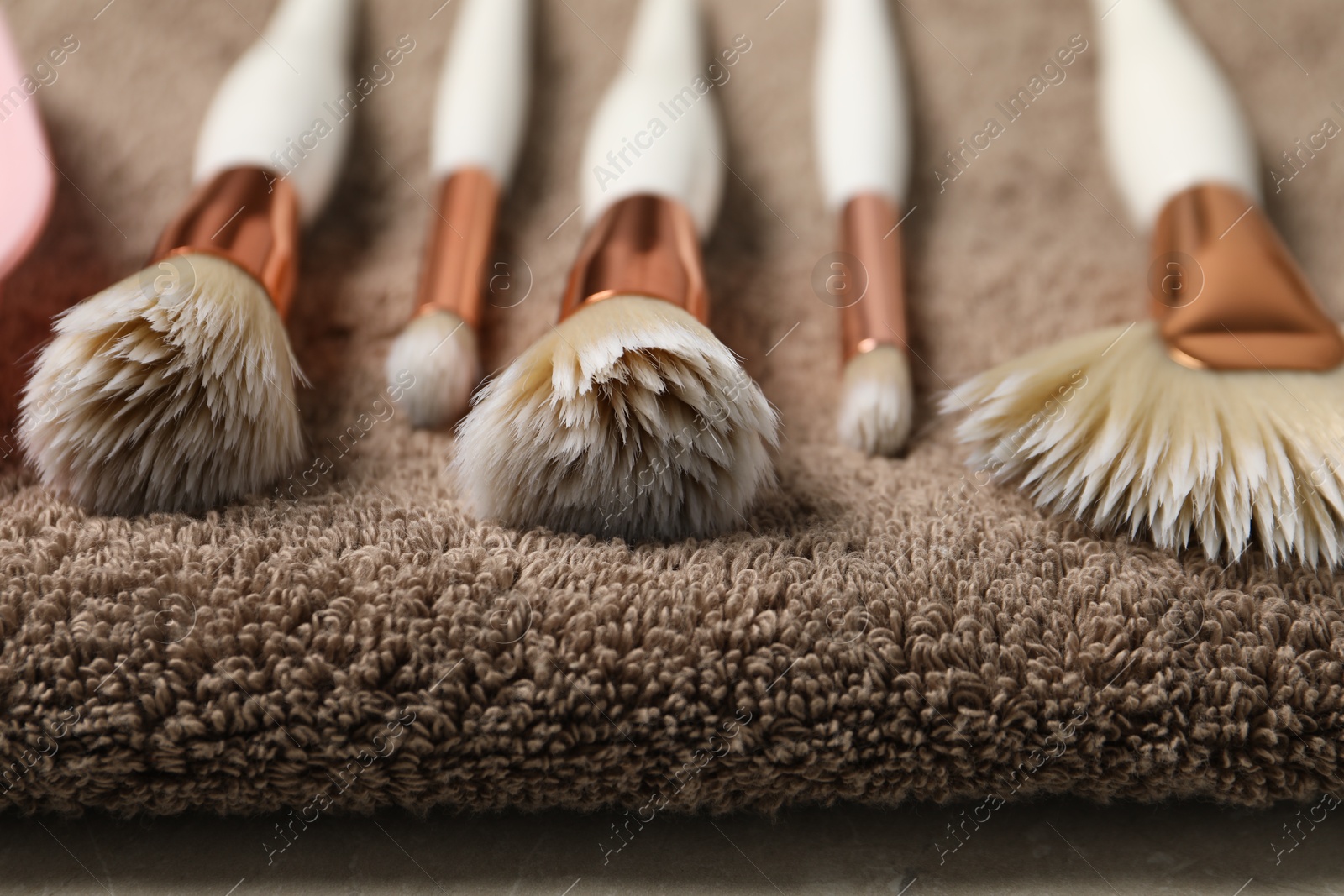 Photo of Clean makeup brushes on brown towel, closeup