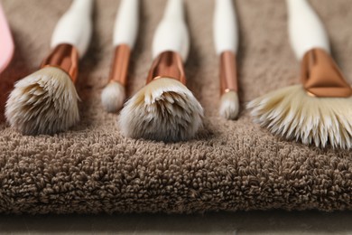 Photo of Clean makeup brushes on brown towel, closeup