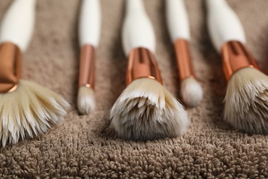 Photo of Clean makeup brushes on brown towel, closeup