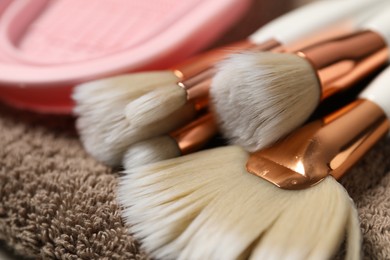 Photo of Clean makeup brushes on brown towel, closeup