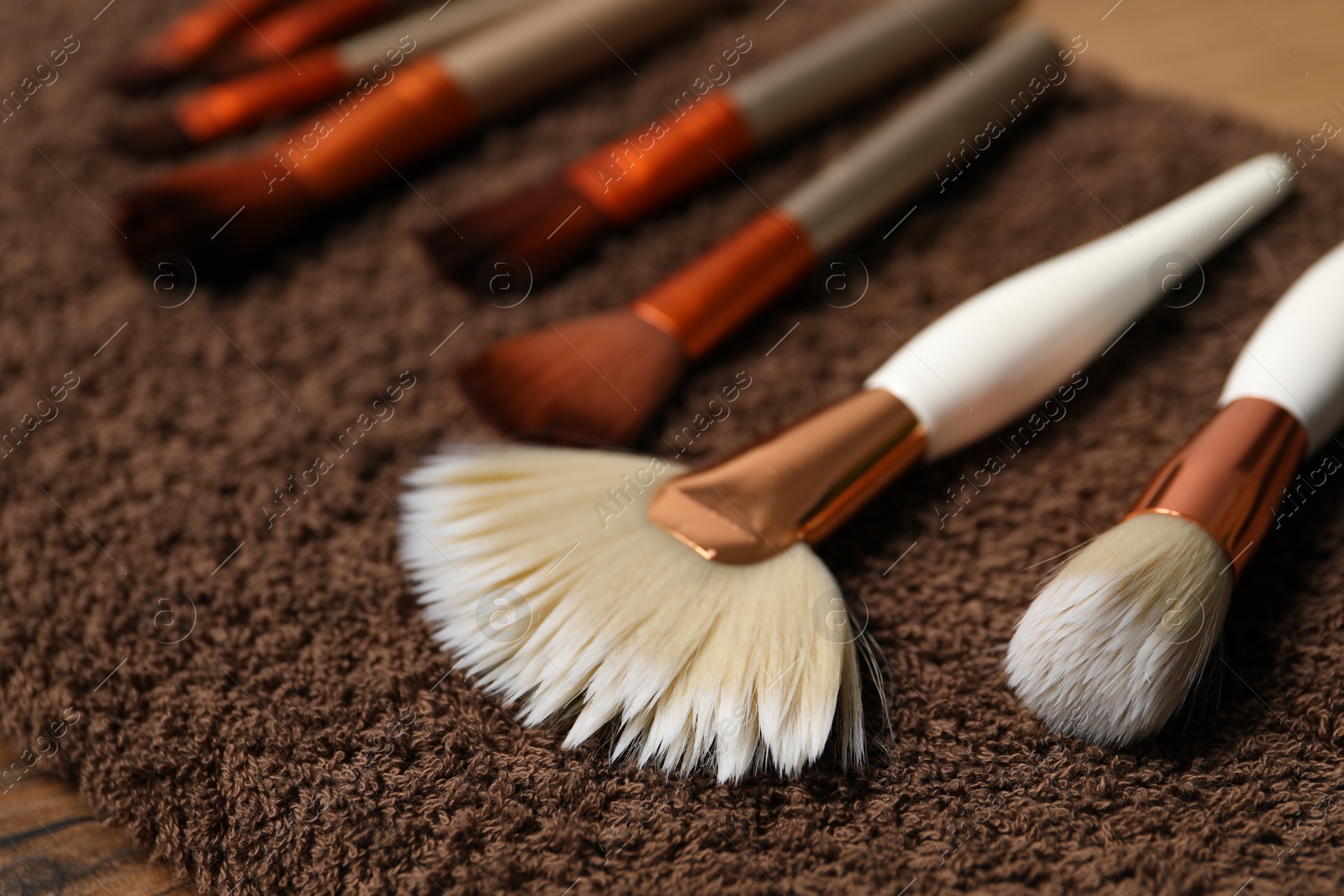 Photo of Clean makeup brushes on brown towel, closeup