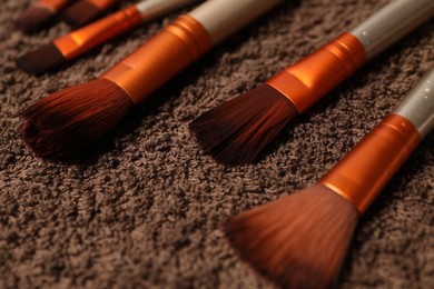 Photo of Clean makeup brushes on brown towel, closeup