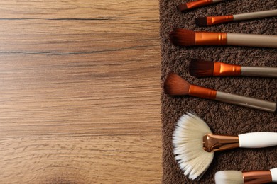 Photo of Clean makeup brushes on wooden table, above view. Space for text