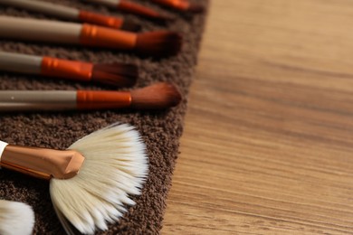 Photo of Clean makeup brushes on wooden table, closeup. Space for text