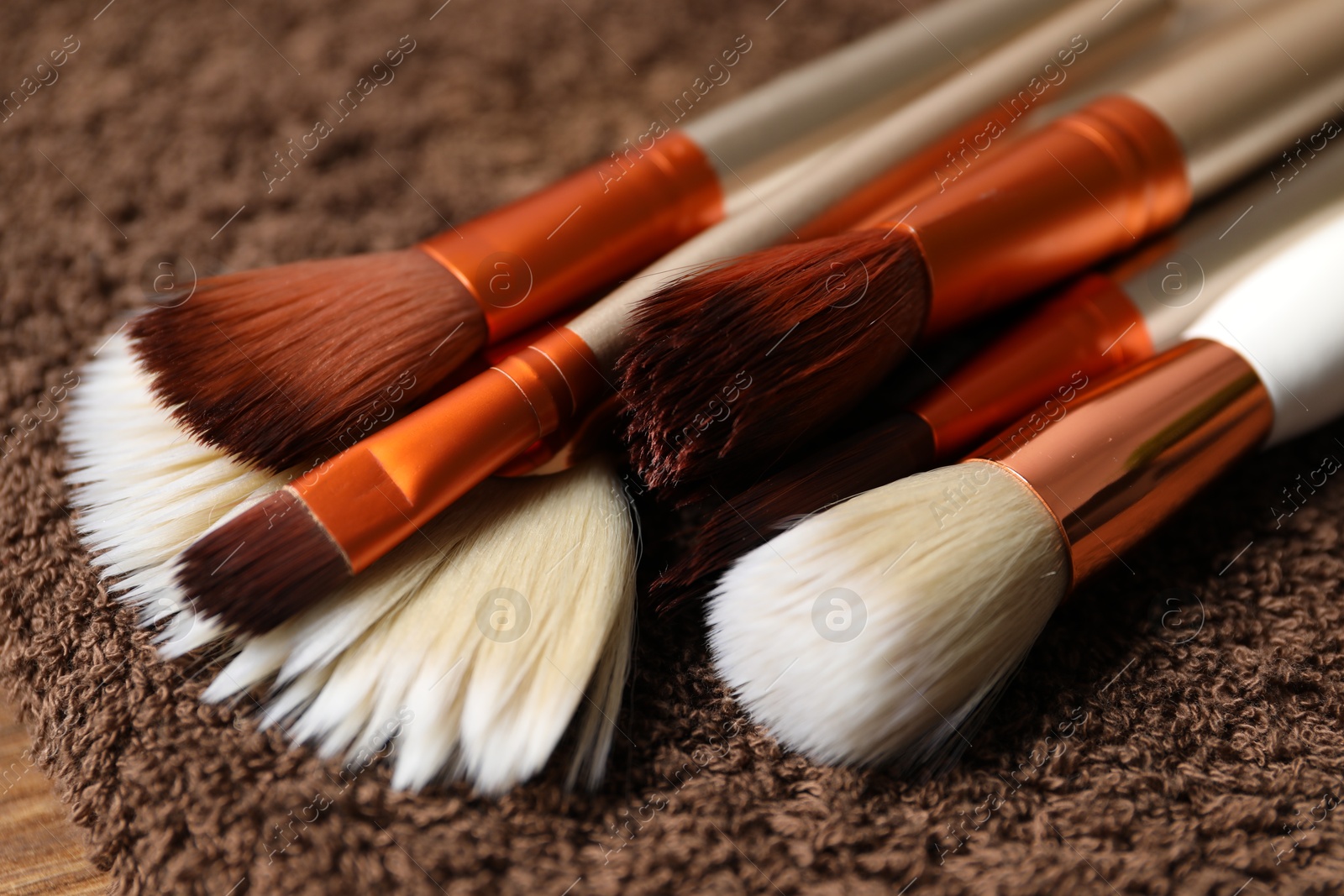 Photo of Clean makeup brushes on brown towel, closeup