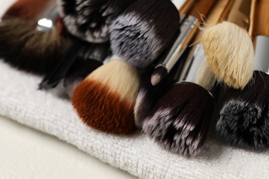 Photo of Clean makeup brushes on white table, closeup