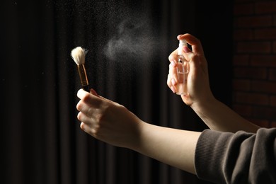 Photo of Woman cleaning makeup brush with spray indoors, closeup