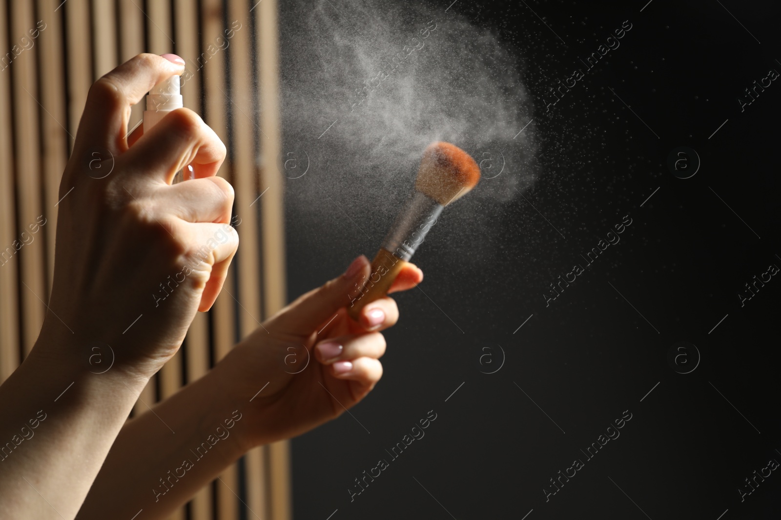 Photo of Woman cleaning makeup brush with spray indoors, closeup. Space for text