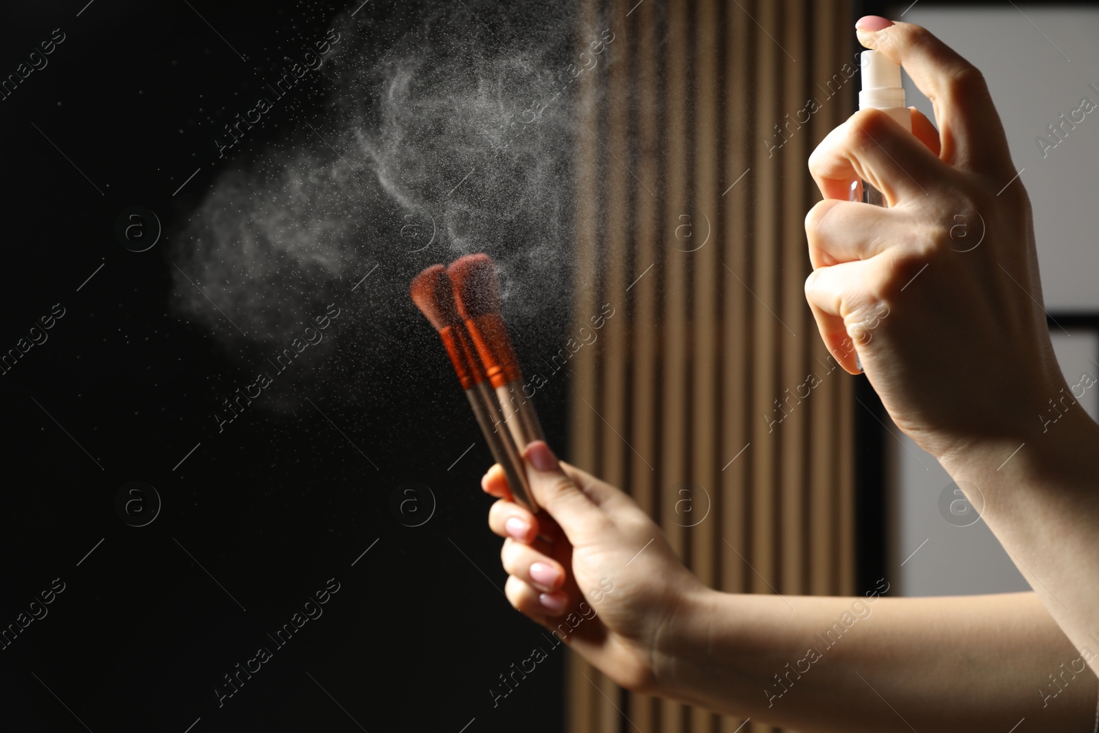 Photo of Woman cleaning makeup brushes with spray indoors, closeup. Space for text